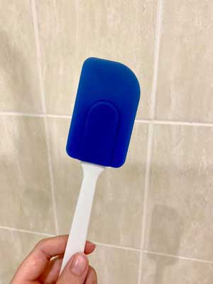 hand holding a blue spatula